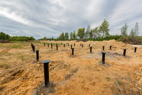 IJzeren schroeven stapels in de grond voor een nieuw gebouw op de bouwplaats. Rechtenvrije Stockafbeeldingen