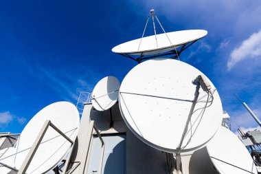 Arkaplan olarak mavi gökyüzü ile uydu antenleri.
