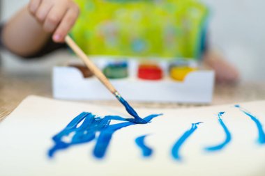 Küçük çocuğun üst görüntüsü kağıda parlak boyalar çiziyor.