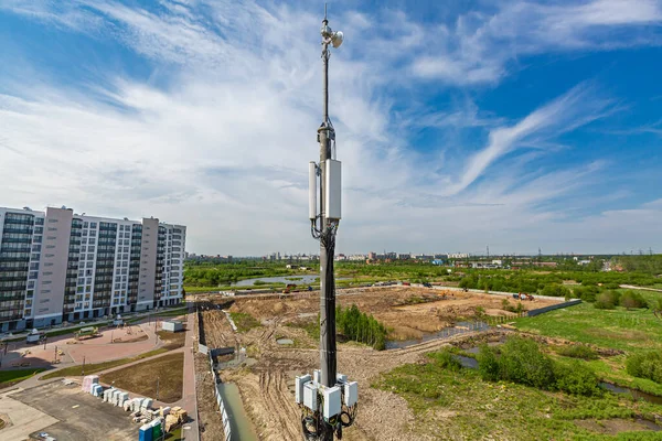 Torre de telecomunicaciones con equipo de microondas 5G, antenas de panel de radio, unidades de radio remotas al aire libre, cables de alimentación, cables coaxiales, fibras ópticas, gabinetes a prueba de vándalos climáticos están instalados en el Fotos De Stock Sin Royalties Gratis