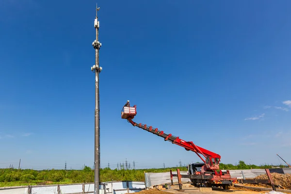Engineer starts working on the telecommunication tower -cellular phone repeater mast - from An aerial work platform, also known as an aerial device, elevating work platform, cherry picker, bucket