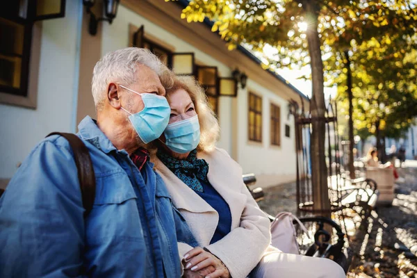 Słodka Para Seniorów Maskami Ochronnymi Siedząca Ławce Zewnątrz Trzymająca Się — Zdjęcie stockowe