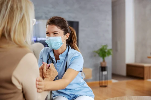 Friendly Nurse Protective Mask Face Sitting Home Senior Woman Comforting — Stock Photo, Image