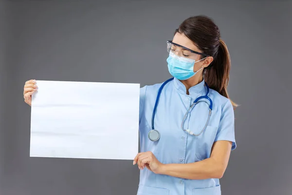 Jovem Médica Com Máscara Protetora Segurando Papel Branco Olhando Para — Fotografia de Stock