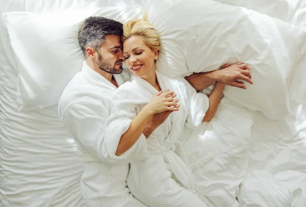사랑에 부부가 침대에 누워서 껴안고 여행을 즐기는 — 스톡 사진