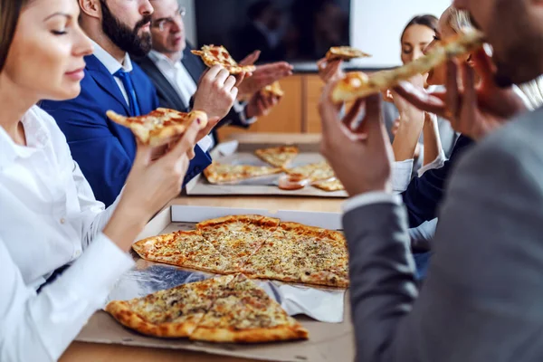 役員室に座っている間に昼食のためのピザを持っている空腹のビジネスの人々のグループ — ストック写真