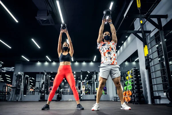 Muskulösa Sportiga Par Form Med Ansiktsmasker Lyfta Kettlebells När Står — Stockfoto