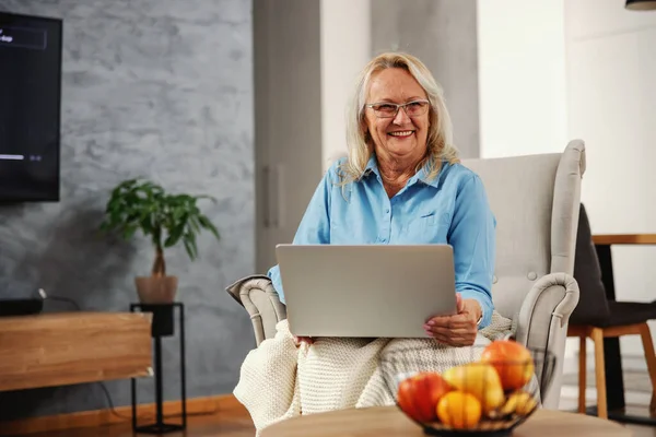 Lächelnde Seniorin Sitzt Hause Stuhl Laptop Auf Dem Schoß Und — Stockfoto