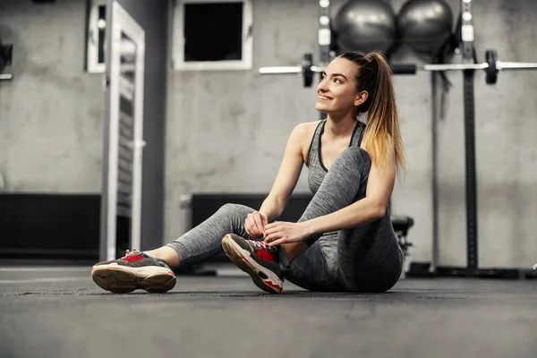 Tying Shoelaces Sneakers Training Girl Gray Sportswear Sits Floor Indoor — Stock Photo, Image