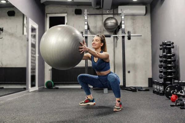 Kuca Dużą Szarą Piłką Atrakcyjna Kobieta Odzieży Sportowej Wykonuje Ćwiczenia — Zdjęcie stockowe