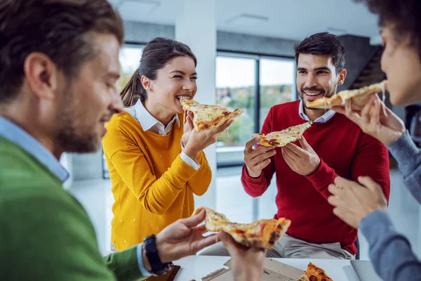 ピザの時間だ 昼食のためにピザを食べるオフィスに立っているビジネスマンの興奮多文化グループ 休憩中のチームビルディング 笑顔の女性はちょうどピザを一口食べた — ストック写真