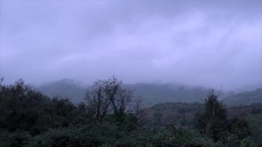 Gri ve yağmurlu bir günde, bir sonbahar sabahı, sislerin arasında dağların manzarası
