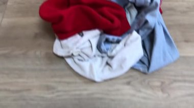 Bir gencin çamaşırlarını çeşitli renkli kıyafetlerle sepetten çamaşır sepetine taşımak.