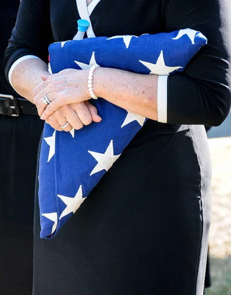 A mourner clutches a folded American flag at the military funeral of a loved onel