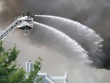 İtfaiyeciler kulede yanan bir binanın üzerine su püskürtüyorlar..