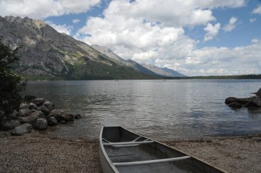 Sahilde Grand Teton Ulusal Parkı, Montana, ABD 'deki Jenny Gölü' ne fırlatılmaya hazır bir kano var.