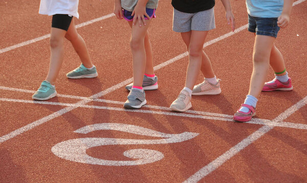 Closeup of children's legs on a starting line of a running track.