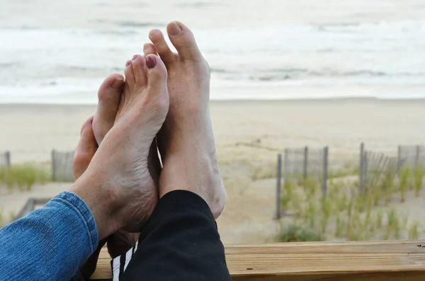 A romantic couple's feet touching at an oceanfront location.