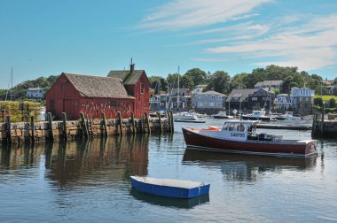 Rockport, Massachusetts Limanı 'nda ön planda demirli tekneleri olan Motif # 1 olarak bilinen kırmızı balıkçı kulübesi..