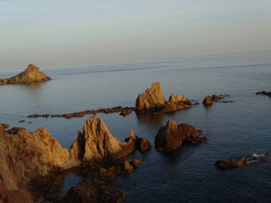 Denizin ortasında kayalar beliriyor.