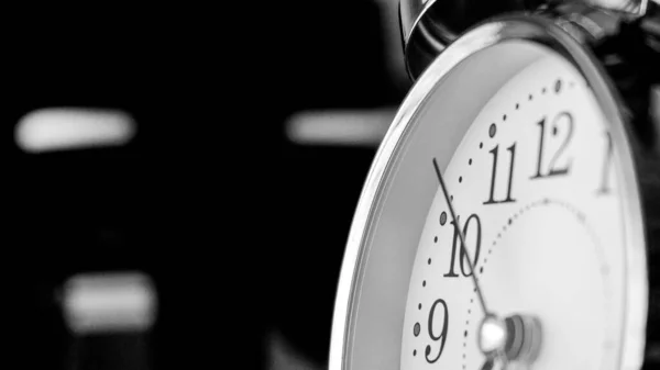 Black white big metallic clock close up. Time or showing time concept. Classic retro mechanical alarm clock with ringer. Time passing or waking up in the morning