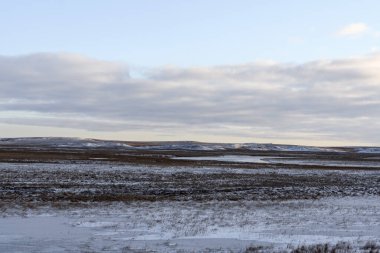Kış zamanı kutup manzarası. Tundra 'da buzlu küçük bir nehir.
