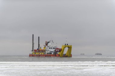 Gün batımında tarama yapan bir gemi. Hopper dredger denizde çalışıyor. Bir su ortamından kazı malzemesi..