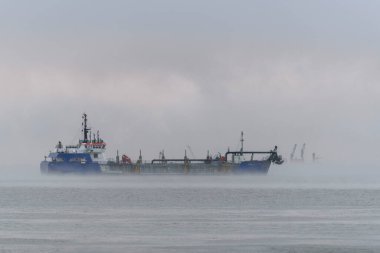 Gün batımında tarama yapan bir gemi. Hopper dredger denizde çalışıyor. Bir su ortamından kazı malzemesi..