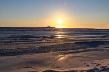 Kış zamanı kutup manzarası. Tundra 'da buzlu küçük bir nehir. Gün batımı.
