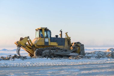 Kış tundrasında sarı traktör. Yol inşaatı. Buldozer.