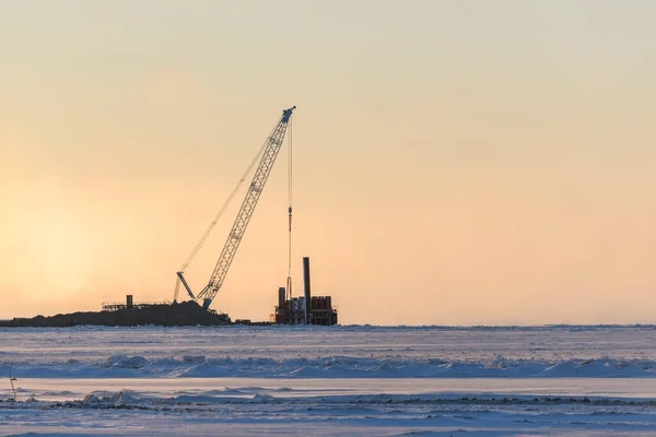 Barge with crane. Dredger working at sea. Sunset in Arctic sea. Construction Marine offshore works. Dam building, crane, barge, dredger.