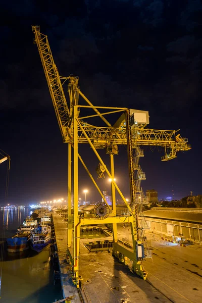 Gantry crane in port at night time. Yellow crane and dark sky.