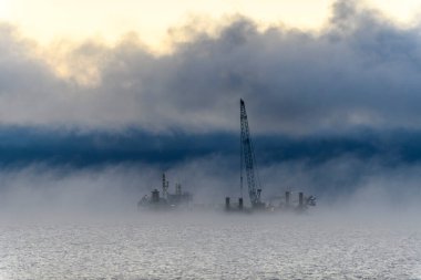 Gemi tarama yapıyor. Dredger denizde çalışıyor. Su ortamında kazı yapan bir gemi. Kuzey Kutup Denizi 'nde yoğun sis var. Deniz aşırı inşaat işleri. Baraj inşaatı, vinç, mavna, eşeleme.