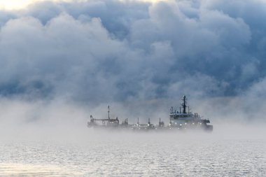 Gemi tarama yapıyor. Dredger denizde çalışıyor. Su ortamında kazı yapan bir gemi. Kuzey Kutup Denizi 'nde yoğun sis var. Deniz aşırı inşaat işleri. Baraj inşaatı, vinç, mavna, eşeleme.