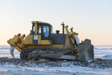 Kış tundrasında sarı traktör. Yol inşaatı. Buldozer.