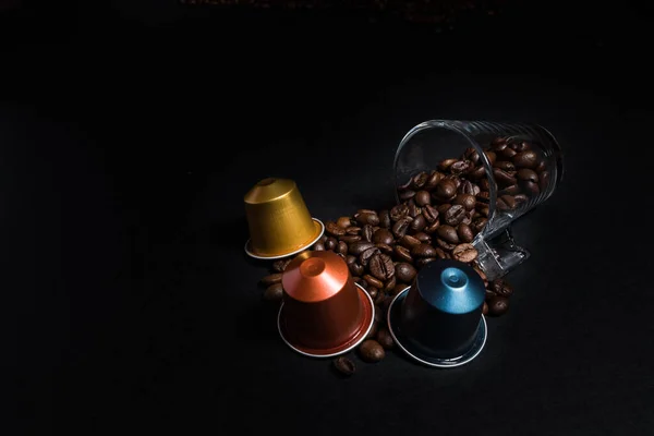 Abstract and conceptual of home coffee capsule machines with coffee beans and coffee cup. Collection of espresso coffee capsules isolated on black background, close-up view details. Graphic resources with copy space.