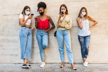 Sadece akıllı telefon kullanarak yüz maskesi takan çok ırklı genç kadınları gruplara ayırın - Sadece akıllı telefon kullanarak yüz maskeli genç kızları gruplara ayırın - akıllı telefon kullanan çok ırklı genç kadınları gruplara ayırın