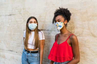 Corona virüsünün yayılmasını önlemek için yüz koruyucu maske takan kadınlar - Coronavirus salgını sırasında genç kadın portresi - Sağlık hizmetleri kadınları ve gençlerin çok ırklı yaşam tarzı arkadaşlık kavramı