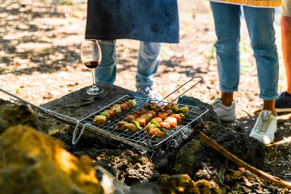 Friends having a barbecue party in nature while having a blast. Food, people and family time concept  young people cooking meat on barbecue grill at summer garden party.