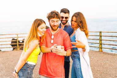 Akıllı telefon kullanan arkadaşlar grubu - İnsanlar cep telefonuna bağımlı olan elleri - Milenyumlarla bağlantılı teknoloji kavramı - Sosyal medya ağlarında içeriği paylaşan genç milenyum insanları 