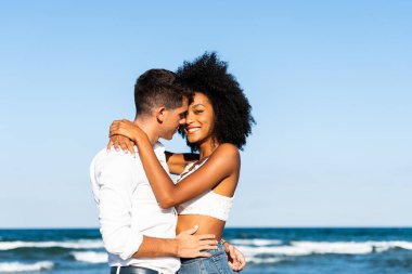 Genç romantik çift güneşli bir günde kumsalda eğleniyor. Delicesine aşık. Deniz arka planı. Romantik genç çiftin yakın çekimi açık havada öpüşmek ve eğlenmek..