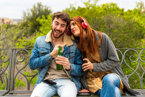 Young Couple Listening Music Headphones Sitting Bench Park Drinking Beer — Foto Stock
