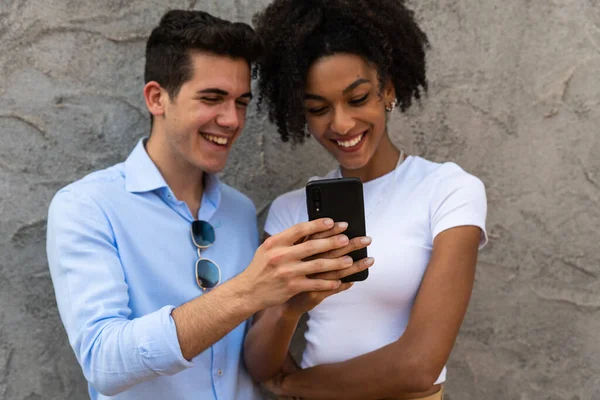 Uśmiechnięta Młoda Para Obejmująca Się Patrząc Smartfona Wieloetniczna Para Dzieląca — Zdjęcie stockowe