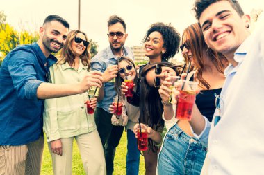 Parkta parti için toplanmış bir grup mutlu genç arkadaş parti sırasında içki içip selfie çeken heyecanlı insanlar..