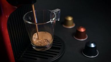 Kahve makinesiyle kahve makinesini şeffaf bardağa çevirme işlemi, otomatik kahve makinesinden çıkan espresso kahvesi. Kahvaltıda içecek. Siyah arkaplanda.