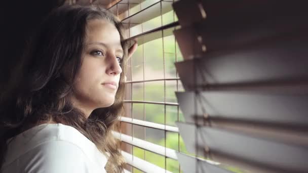 Chica mirando por la ventana — Vídeo de stock