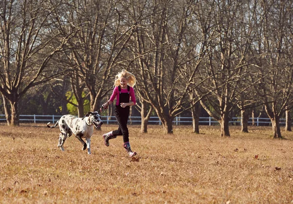 Girl with dog running in field — Stock Photo, Image