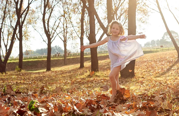 Menina correndo em folhas de outono — Fotografia de Stock
