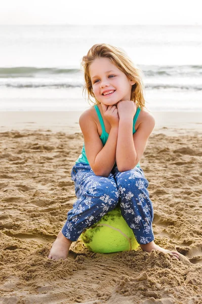 Девушка сидит на мяче на пляже — стоковое фото