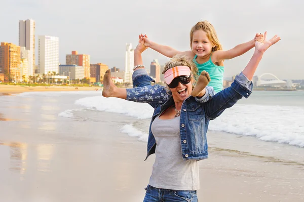 girl sitting on mother\'s shoulders